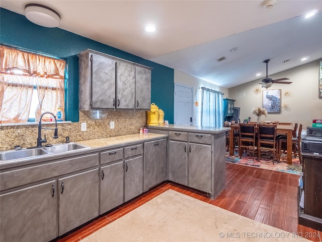 kitchen with dark wood finished floors, lofted ceiling, light countertops, a sink, and a peninsula