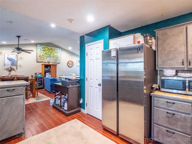 kitchen with lofted ceiling, ceiling fan, light wood-type flooring, and stainless steel appliances