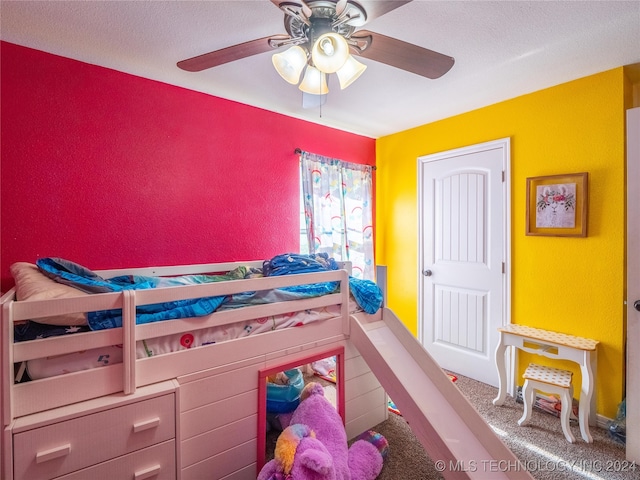 bedroom with ceiling fan, carpet floors, and a textured ceiling