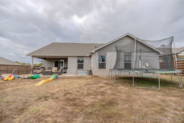 back of property with a patio, a trampoline, and a lawn