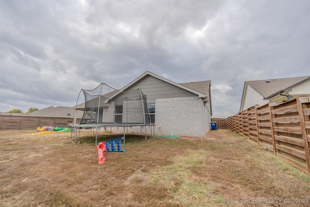 back of property featuring a yard and a trampoline