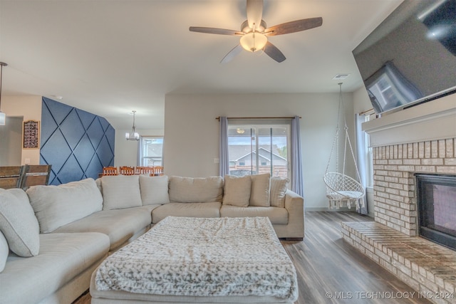 living room with a fireplace, ceiling fan with notable chandelier, and hardwood / wood-style floors