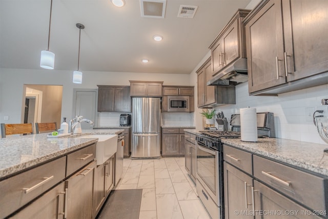 kitchen with appliances with stainless steel finishes, sink, pendant lighting, light stone counters, and decorative backsplash