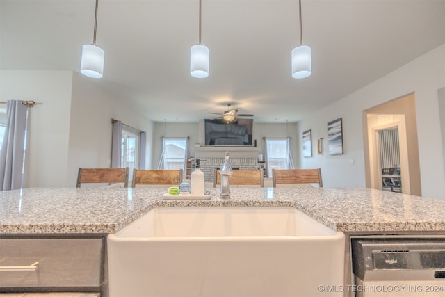 kitchen featuring sink, dishwasher, ceiling fan, pendant lighting, and a breakfast bar