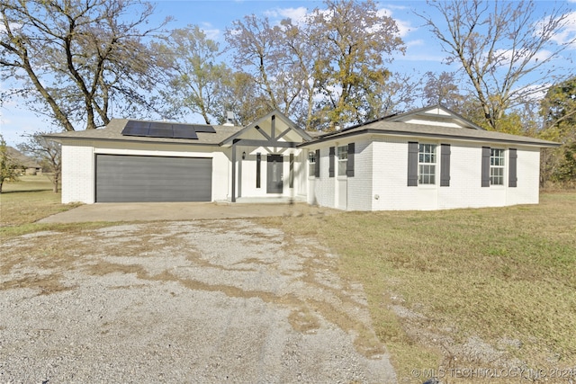 view of front of home with a garage, solar panels, and a front yard