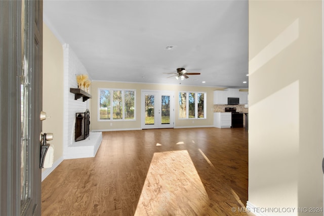 unfurnished living room with dark wood-type flooring, ceiling fan, and a brick fireplace