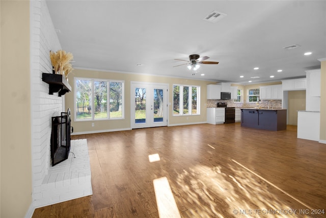 unfurnished living room with a brick fireplace, dark hardwood / wood-style floors, crown molding, and ceiling fan