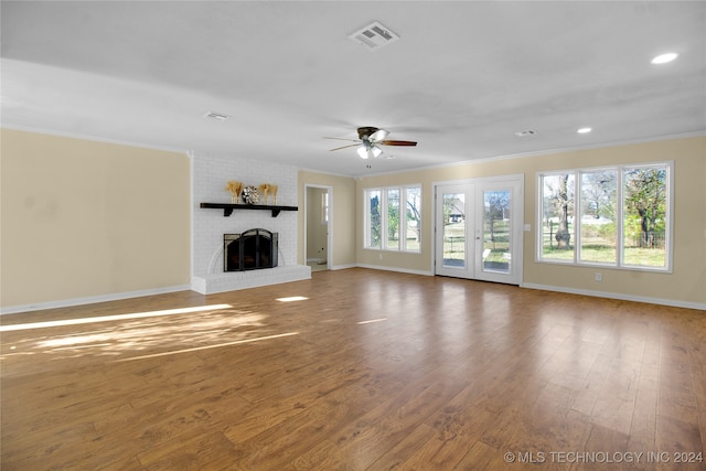 unfurnished living room with a brick fireplace, hardwood / wood-style floors, a wealth of natural light, and ceiling fan