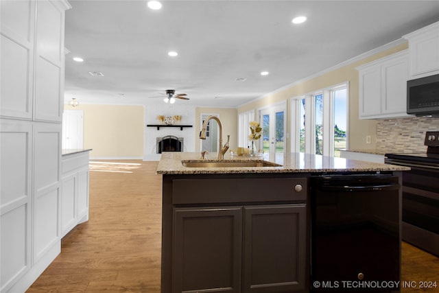 kitchen featuring stainless steel appliances, light stone countertops, sink, white cabinets, and light hardwood / wood-style flooring