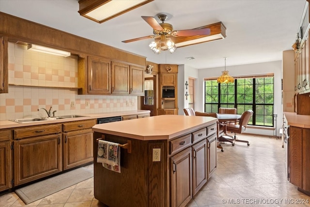 kitchen featuring tasteful backsplash, hanging light fixtures, ceiling fan, sink, and a center island