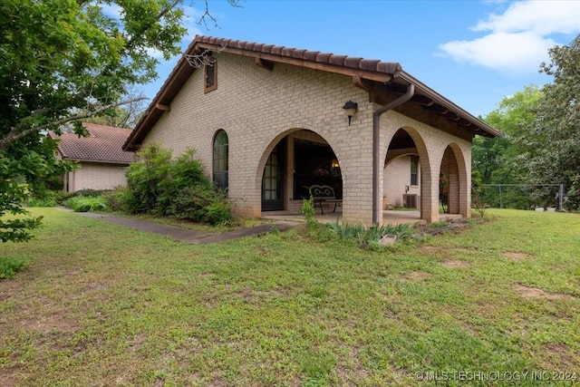 back of house with cooling unit, a patio area, and a lawn