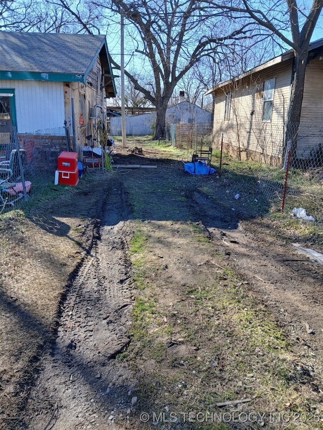 view of yard featuring fence and dirt driveway