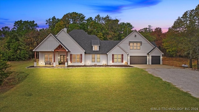 modern farmhouse featuring a garage, a porch, and a yard