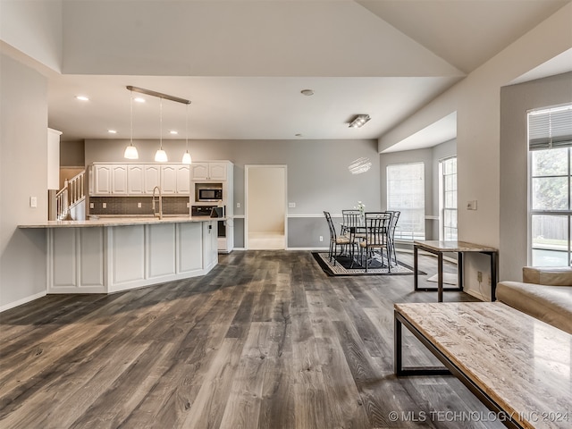 kitchen featuring a wealth of natural light, stainless steel microwave, white cabinetry, and hanging light fixtures