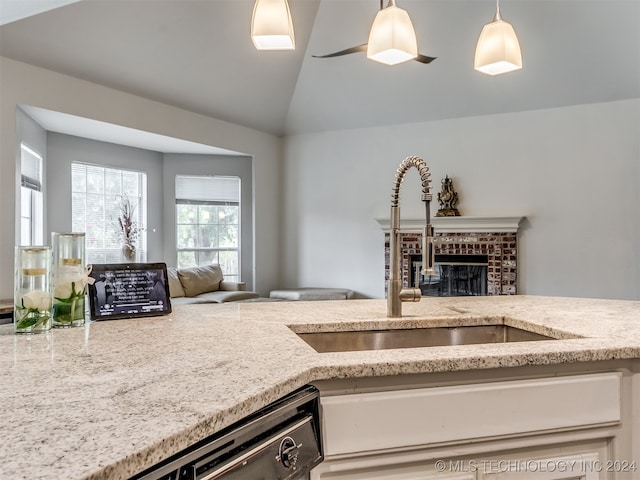 kitchen with dishwasher, sink, hanging light fixtures, a brick fireplace, and vaulted ceiling