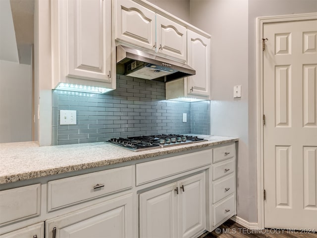 kitchen with backsplash, white cabinetry, light stone counters, and stainless steel gas cooktop