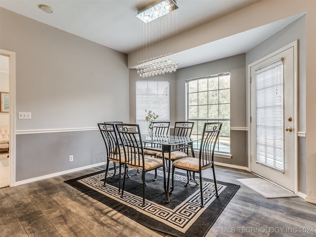 dining space featuring a healthy amount of sunlight, dark hardwood / wood-style flooring, and an inviting chandelier