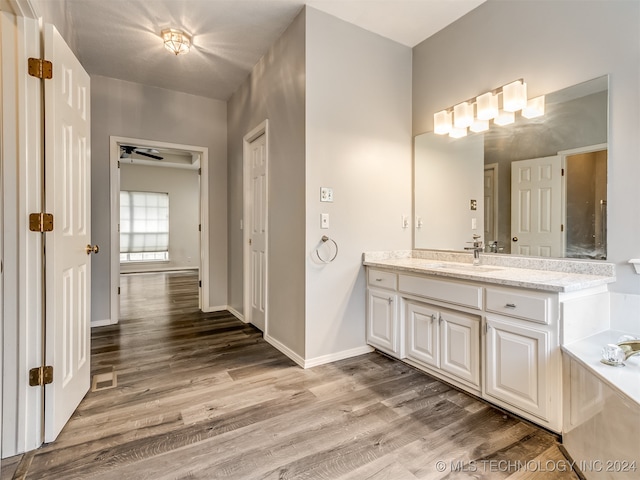 bathroom with vanity, ceiling fan, wood-type flooring, and a tub