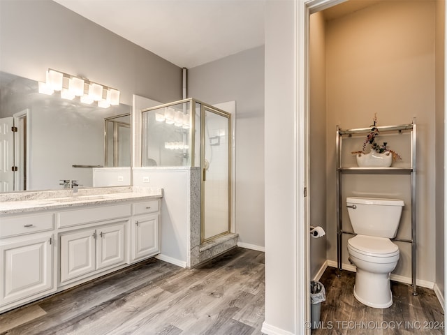 bathroom with hardwood / wood-style flooring, a shower with door, vanity, and toilet