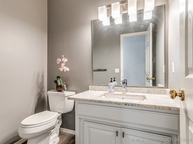 bathroom with wood-type flooring, vanity, and toilet