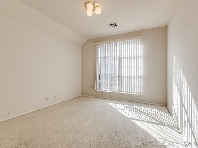 empty room featuring light colored carpet and lofted ceiling