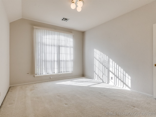 carpeted spare room featuring lofted ceiling