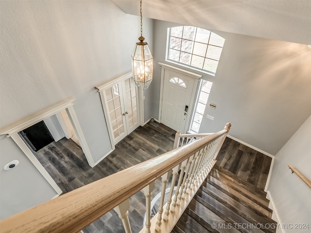 foyer entrance featuring high vaulted ceiling, dark wood-type flooring, and an inviting chandelier