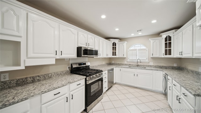 kitchen featuring light stone countertops, sink, stainless steel appliances, white cabinets, and light tile patterned floors