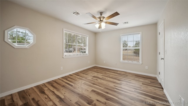 empty room with ceiling fan, plenty of natural light, and hardwood / wood-style floors