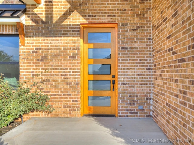 entrance to property featuring a patio and brick siding