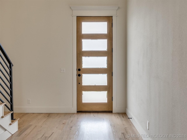 foyer entrance featuring stairs, light wood-style flooring, and a healthy amount of sunlight