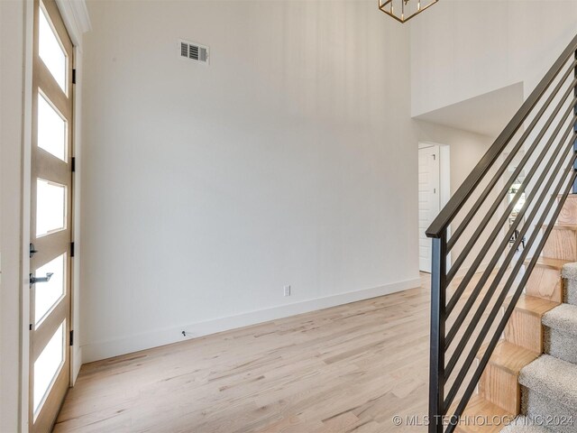 interior space with a notable chandelier, hardwood / wood-style flooring, and a towering ceiling