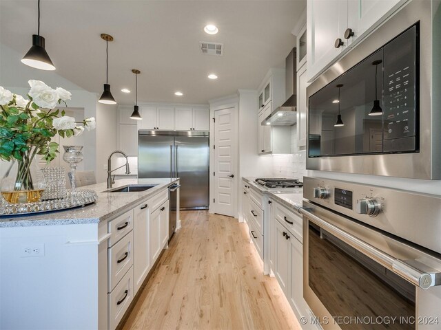 kitchen featuring built in appliances, white cabinetry, and sink