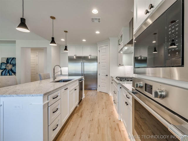 kitchen with light wood finished floors, stainless steel appliances, visible vents, white cabinetry, and a sink