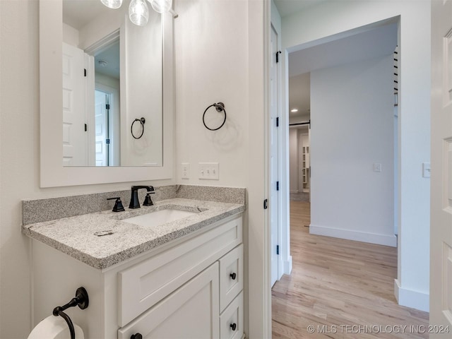 bathroom with baseboards, wood finished floors, and vanity