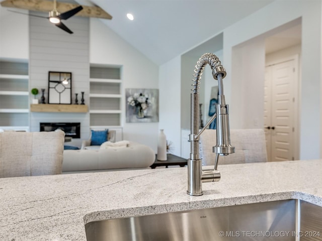 details with light stone counters, recessed lighting, a large fireplace, and a sink