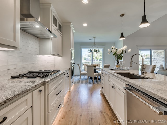 kitchen with wall chimney exhaust hood, appliances with stainless steel finishes, a healthy amount of sunlight, and white cabinetry