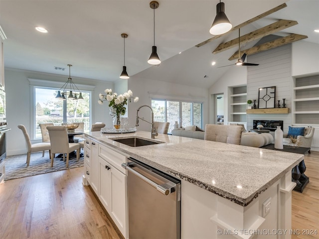 kitchen featuring appliances with stainless steel finishes, beamed ceiling, a kitchen island with sink, light wood-type flooring, and a sink