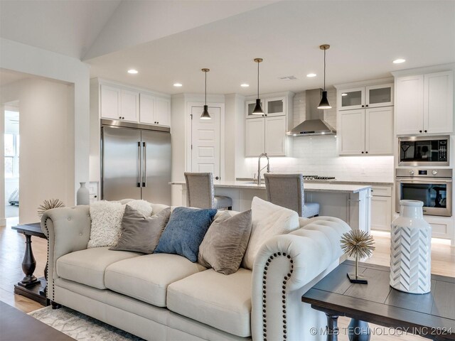 living room with sink, lofted ceiling, and light hardwood / wood-style flooring