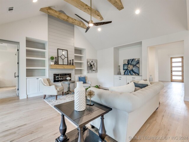 living room featuring light wood-type flooring, a fireplace, built in features, beamed ceiling, and high vaulted ceiling