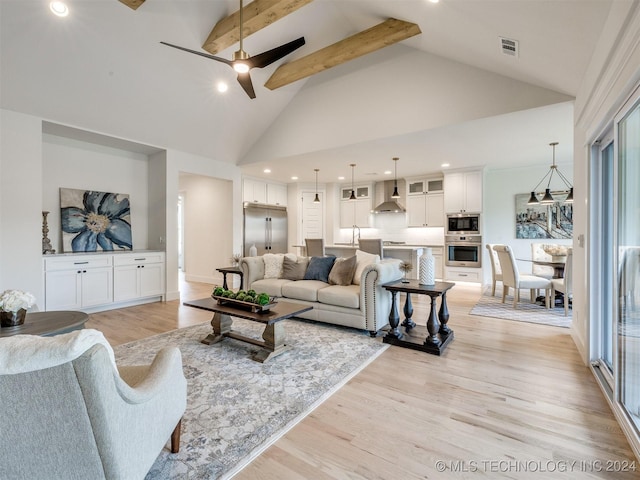 living area with beam ceiling, light wood finished floors, visible vents, a ceiling fan, and high vaulted ceiling