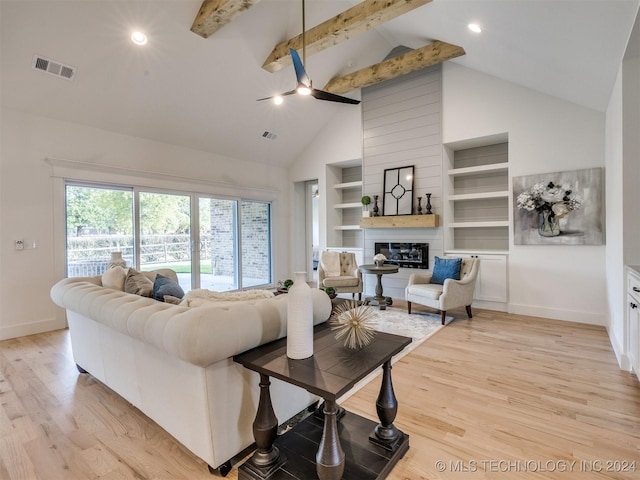 living area featuring visible vents, beamed ceiling, light wood-type flooring, a fireplace, and high vaulted ceiling