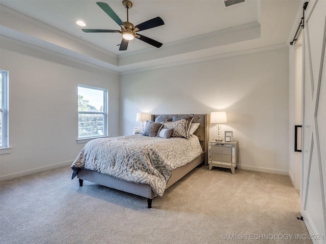 bedroom with a barn door, baseboards, light colored carpet, ornamental molding, and a tray ceiling