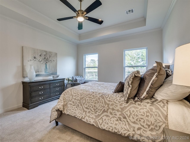 bedroom with visible vents, crown molding, a tray ceiling, and carpet flooring