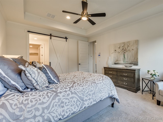 carpeted bedroom with crown molding, a barn door, a tray ceiling, and ceiling fan