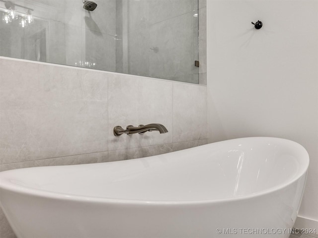 full bathroom featuring a soaking tub, tiled shower, and a sink