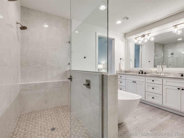 bathroom with vanity, a tile shower, and wood-type flooring