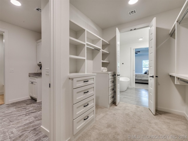 walk in closet featuring light carpet, light wood-type flooring, and visible vents