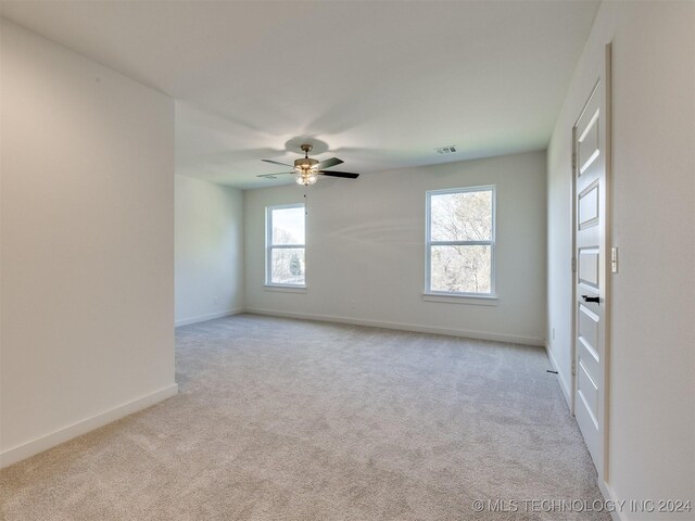 spare room featuring light carpet, plenty of natural light, and ceiling fan