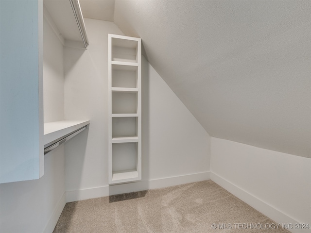 spacious closet featuring lofted ceiling and light colored carpet